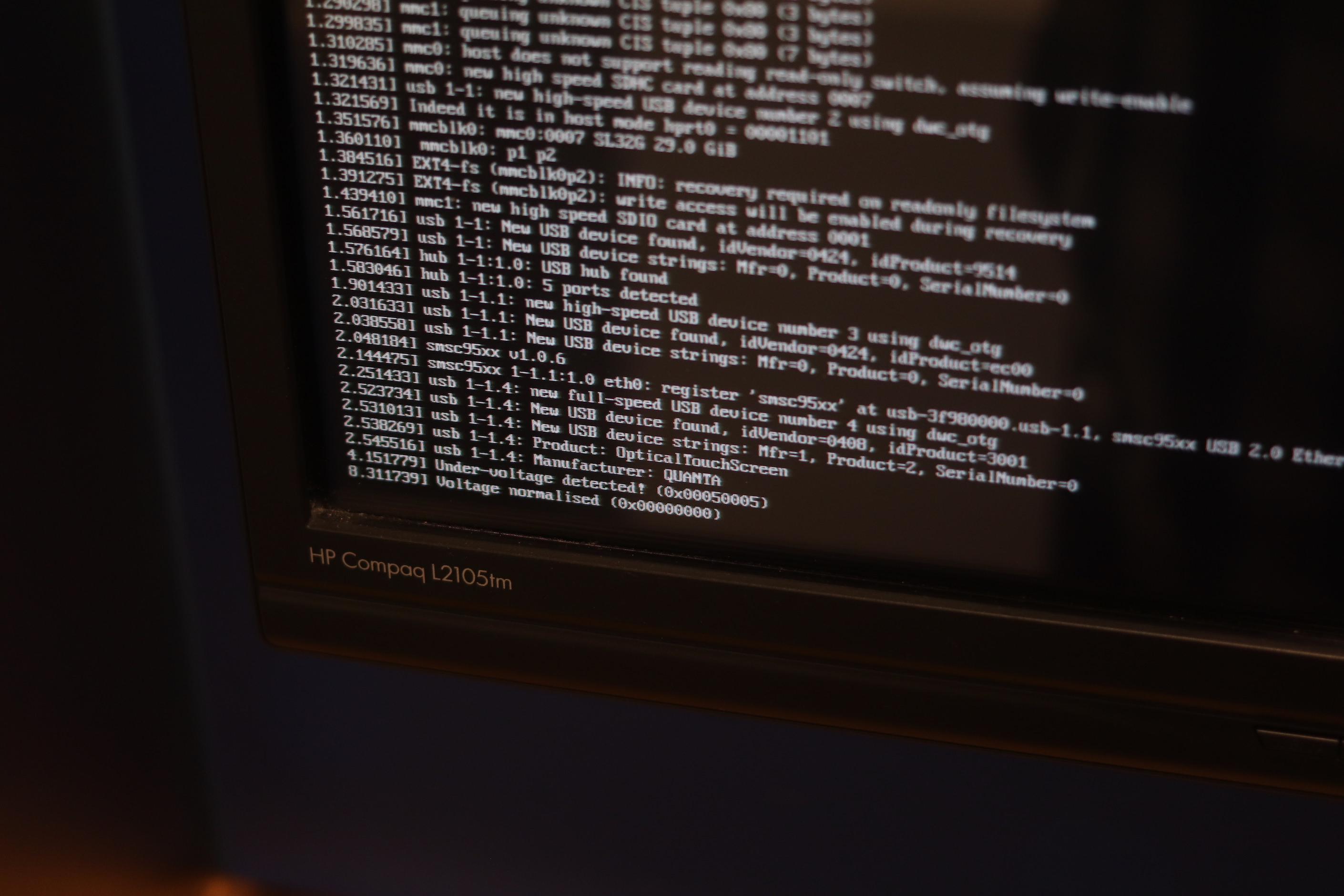 The monitor, showing the Raspberry Pi boot text with references to 'Optical Touch Screen' USB device found.